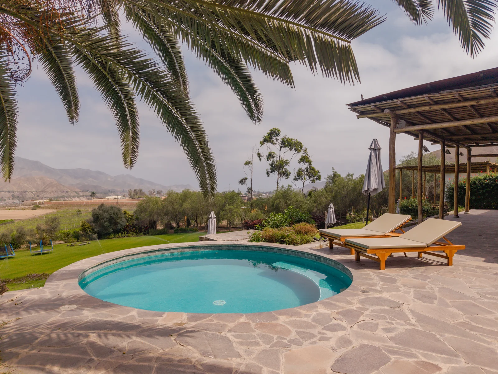 Piscina, palmeras y áreas de descanso de Andenes de Azpitia con vista al valle